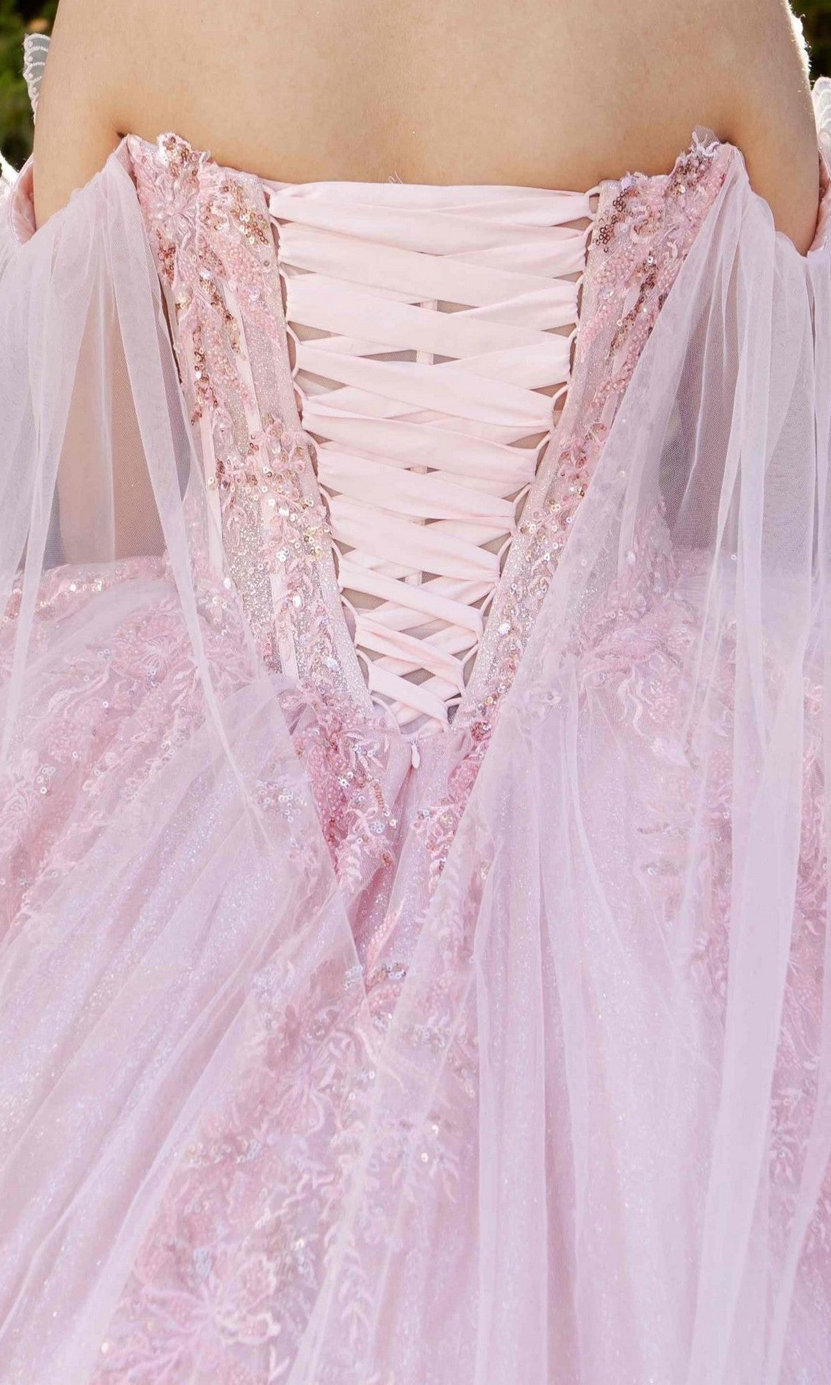 Close-up of the back of the Quinceanera Dress 8270J by Cinderella Couture in pink, featuring a lace-up design, sheer sparkly fabric, off-shoulder sleeves, and beautifully adorned with 3D floral appliques.